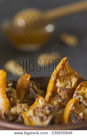 Authentic View Of The Baked Sliced Pumpkin With Honey And Walnuts In A Ceramic Bowl (pial) On A Dark