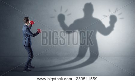 Businessman trying to fight with his unarmed shadow