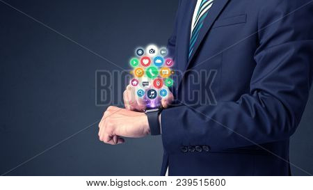 Businessman wearing smartwatch with colored application symbols on it.