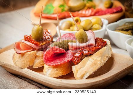 Tapas With Sliced Sausage, Salami, Olives And Parsley.