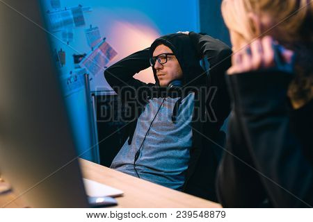 Female Hacker Looking At Depressed Accomplice At Workplace