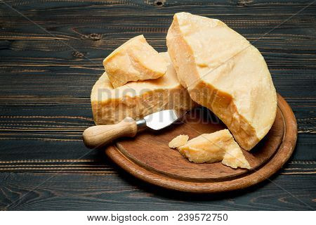 Pieces Of Parmesan Or Parmigiano Hard Cheese And Grapes On Wooden Cutting Board