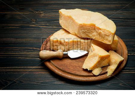 Pieces Of Parmesan Or Parmigiano Hard Cheese And Grapes On Wooden Cutting Board