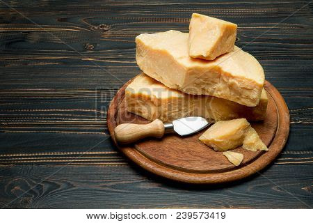 Pieces Of Parmesan Or Parmigiano Hard Cheese And Grapes On Wooden Cutting Board
