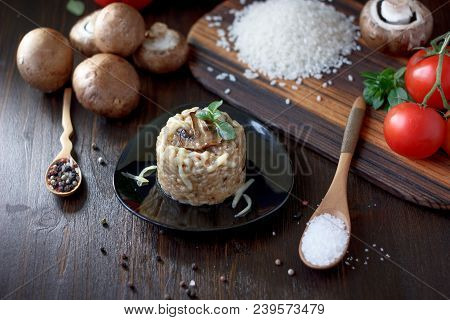 Italian Mushroom Risotto On Black Ceramic Plate Over Table