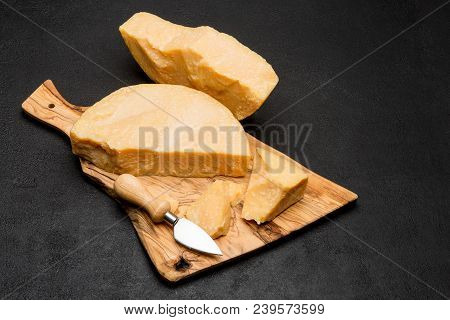 Pieces Of Parmesan Or Parmigiano Hard Cheese And Grapes On Wooden Cutting Board