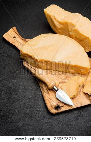 Pieces Of Parmesan Or Parmigiano Hard Cheese And Grapes On Wooden Cutting Board