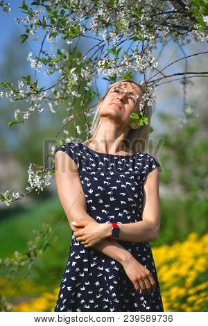 A Portrait Of A Beautiful Young Girl In A Blue Dress In The Garden With Apple Trees Enjoying Smell O