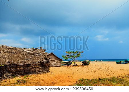Thatched Coconut Leaf House Or Fishing Hut  And Boats On Tropical Beach. Traditional Or Vintage Eco 