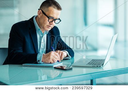 Senior Man Working On Laptop Computer In Office