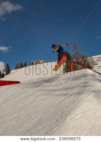 Snowboarder In Action: Jumping In The Mountain Snowpark.