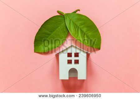 Miniature Toy Model House With Green Leaves On Pink Pastel Colourful Trendy Backgdrop. Eco Village, 