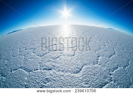 Salar de Uyuni salt flat with salt patterns and sun close to the horizon, Bolivia