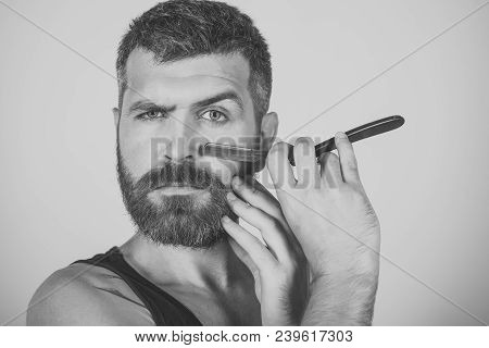 Serious Hipster In Barbershop, New Technology. Man Cut Beard And Mustache With Razor. Barber And Hai