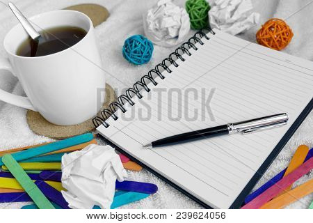 A Mug Of Coffee, Note Pad And Pen On Top Of White Cloth