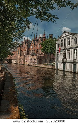 Wooded Gardens And Brick Buildings On The Canal Edge In A Sunny Day At Bruges. With Many Canals And 