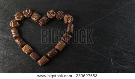 Beautiful Creative Chocolate Heart Shape Made With Various Types Of Pralines Over An Black Stone Bac