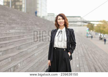 Businesslady Standing On Stairs Outside In High Buildings Background. Concept Of Profession And Busi