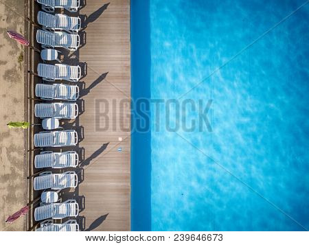 Beach chairs near swimming pool, top view