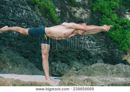 Handsome Man Doing Yoga Near The Beach With Blue Sky And Sea Background. Relaxing And Healthy Lifest