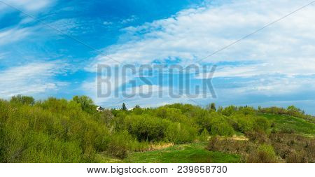 Little House On The Hill On A Background Of Green Trees And Blue Sky With Clouds.