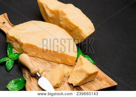 Pieces Of Parmesan Or Parmigiano Hard Cheese And Grapes On Wooden Cutting Board
