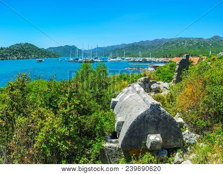 The Blue Waters Of Kekova Bay Behind The Lush Greenery And Ancient Sarcophagus Of Lycian Necropolis 