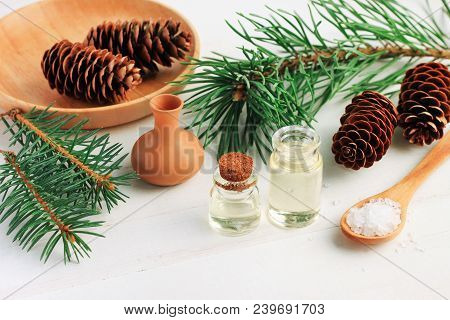 Pine Tree Branches With Essential Oil Bottle And Sea Salt, Viewed Above On White Wooden Table, Cone 