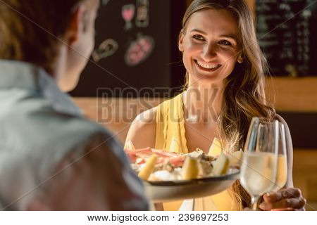 Happy young couple in love toasting with champagne during romantic dinner with seafood as oysters and crabs at the restaurant