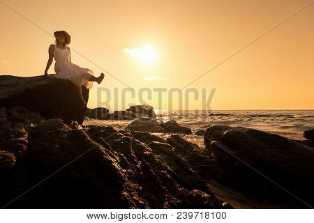 Silhouette Of Asian Beautiful Lady Wear White Dress Is Sit Posing On Rock Cliff.
