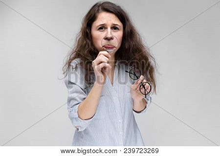 Young Girl With Glasses On A Gray Background. Portrait Of A Young Beautiful Girl. A Charming Girl In