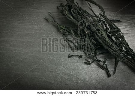 Heap Of Dry Wakame Seaweed On Black Stone Background. Healthy Algae Food With Place For Text