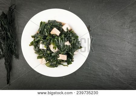 Cooked Wakame Seaweed Salad In White Bowl On Natural Stone Background. Healthy Algae Food With Soy S