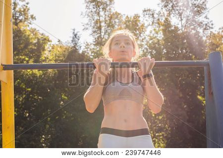 Fit Woman Doing Pull-ups. Young Athletic Fitness Woman Working Out At Outdoor Gym Doing Pull Ups At 
