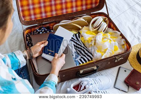 Woman Hands With Watch Put Clothes In Suitcase. Travel Concept. Copy Space. Biometric Passport Lapto