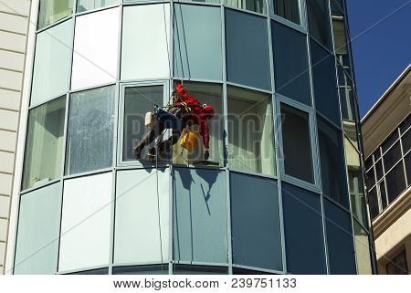 Rope Access Technician In A Helmet Washes The Window Of A High-rise Building From The Outside, Hangi