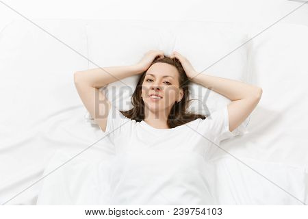 Top View Of Head Of Happy Brunette Young Woman Lying In Bed With White Sheet, Pillow, Blanket. Calm