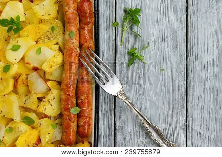 Tasy Baked Potato Slices With Fried Munich Sausages With Basil Leaves On A Baking Sheet