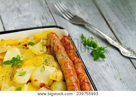 Tasy Baked Potato Slices With Fried Munich Sausages With Basil Leaves On A Baking Sheet