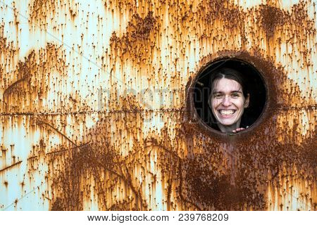Young woman joyfully looks out of the window of an abandoned bunker.