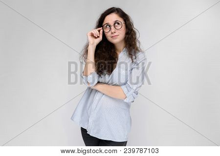 Young Girl Holds Her Hand Glasses. The Girl Is Smiling. The Girl Looks Away.