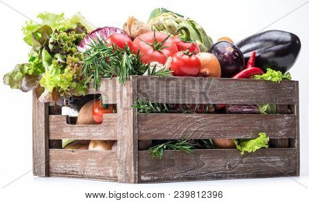 Fresh multi-colored vegetables in wooden crate. White background.