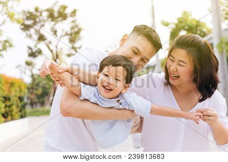 Asian Family Having Fun And Carrying A Child In Public Park