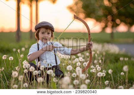 Portrait Of Child Playing With Bow And Arrows, Archery Shoots A Bow At The Target.