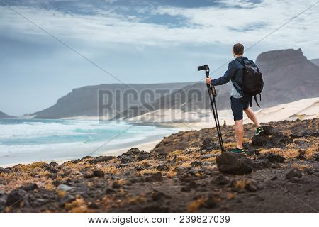 Photographer With Camera On Tripod In Desert Admitting Unique Landscape Of Sand Dunes Volcanic Cliff