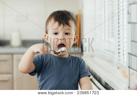 The Little Boy In The Kitchen Eagerly Eating Rice With A Spoon Independently