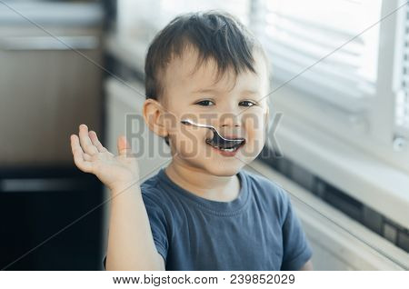 The Little Boy In The Kitchen Eagerly Eating Rice With A Spoon Independently