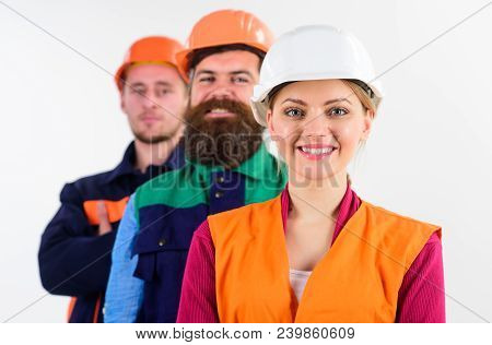 Woman And Men In Hard Hats Stand Close As Team. Builder, Engineer, Labourer As Friendly Team. Equali