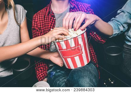 Close Up Of Red With White Basket Of Popcorn That Both Girl And Guy Are Holding. All Of Them Are Tak