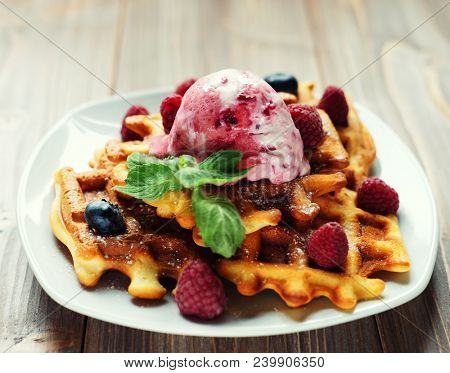 Plate of belgian waffles with ice cream  and fresh berries - raspberries and blueberries.top view close-up.